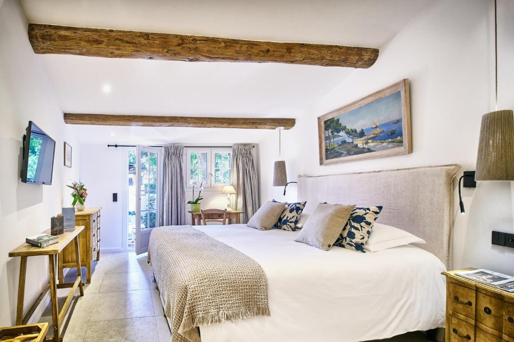 a bedroom with a white bed and a desk at La Ferme D'Augustin in Saint-Tropez