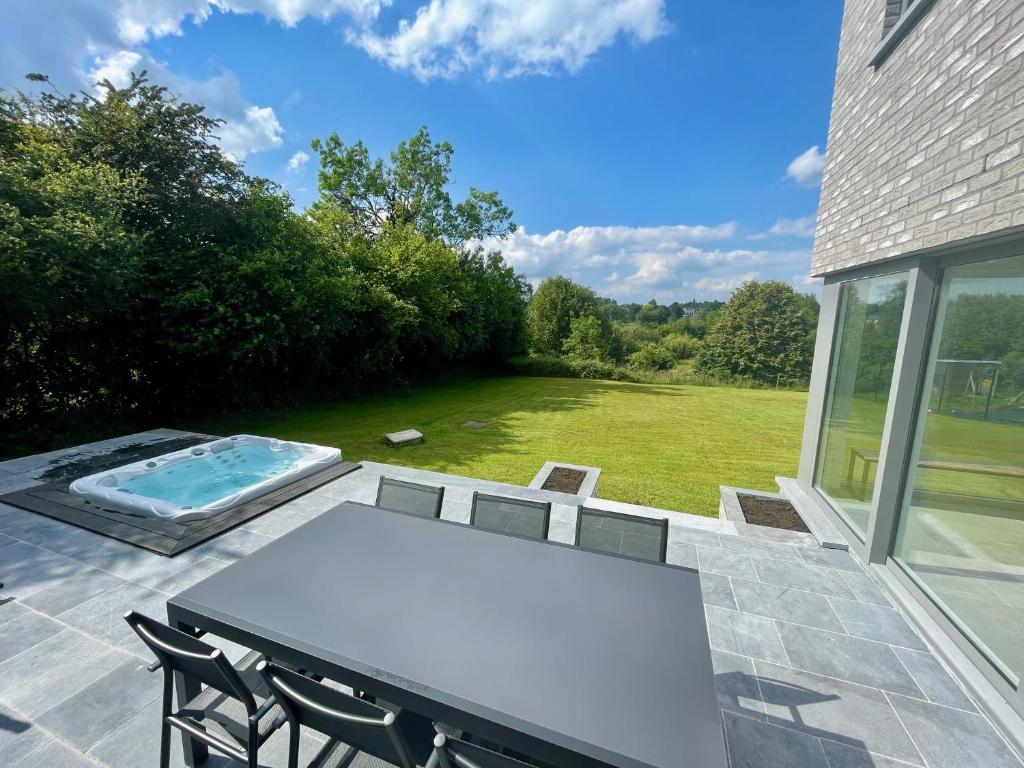 Un patio con mesa y sillas y una piscina. en Gîte Le Mirage - Villa 8 pers - Jacuzzi - Billard - PMR, en Namur