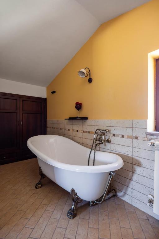 La salle de bains est pourvue d'une baignoire et d'un mur jaune. dans l'établissement Villa Granci con Piscina by Wonderful Italy, à Polizzi Generosa 22 autres photos