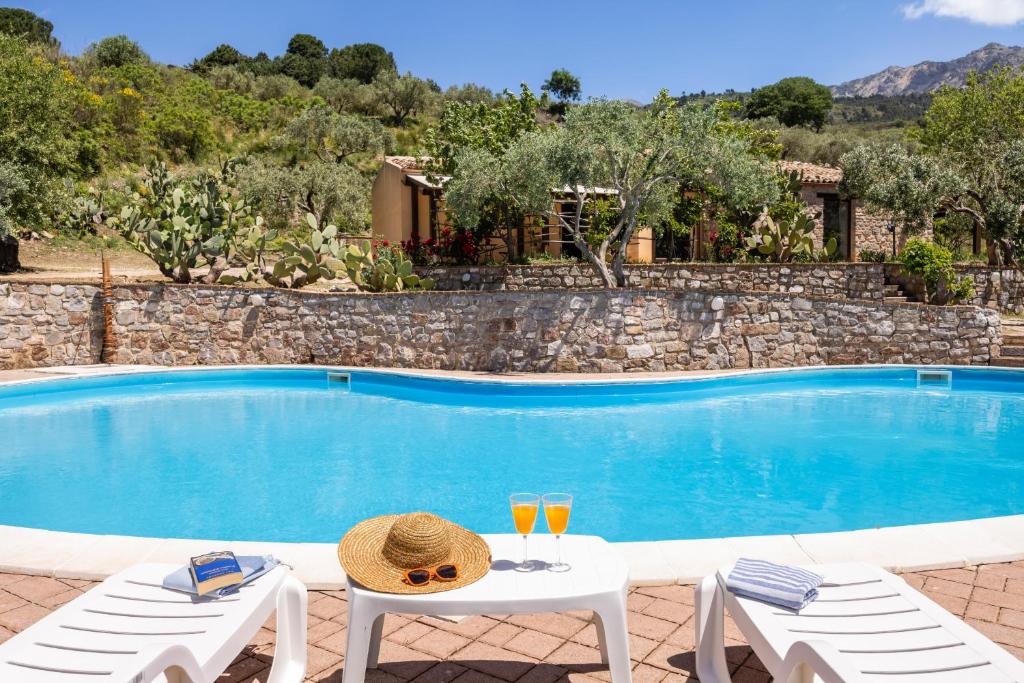 une piscine avec deux chaises et deux verres de vin dans l'établissement Villa Granci con Piscina by Wonderful Italy, à Polizzi Generosa