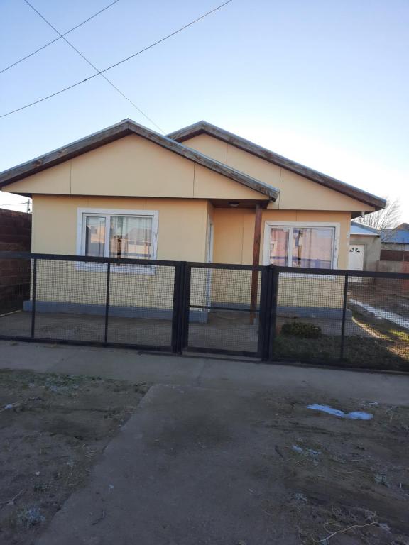 une maison avec une clôture devant dans l'établissement Alojamiento por día, à Puerto San Julian