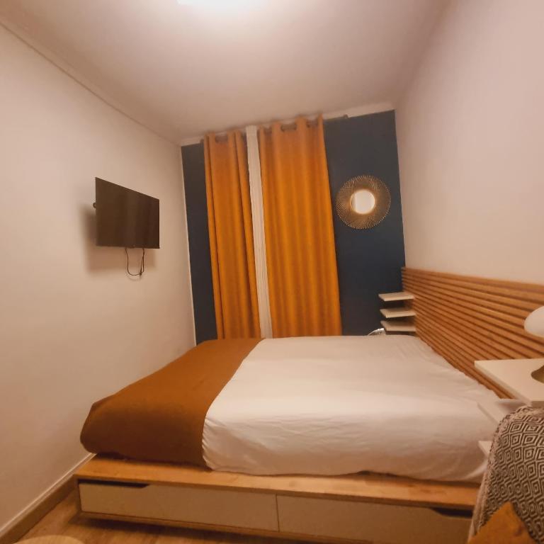 Cette chambre comprend un lit avec des rideaux orange et une télévision. dans l'établissement Joli studio à Bastille, à Paris