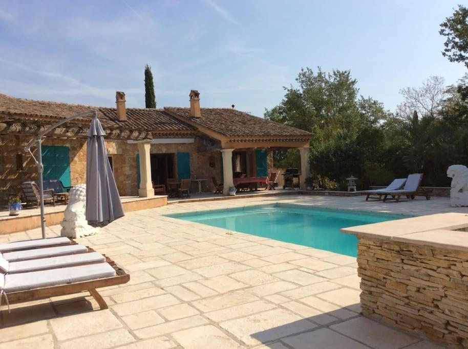 - une piscine avec un parasol et une maison dans l'établissement VILLA Les Oliviers, à Figanières