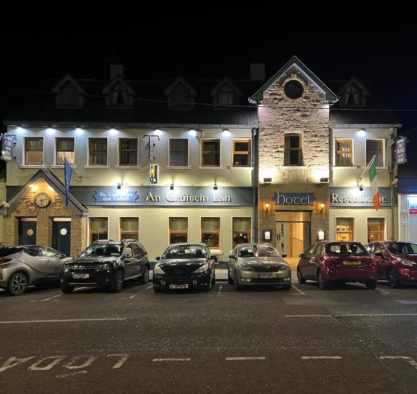 a group of cars parked in a parking lot in front of a building at An Cruiscin Lan in Spiddal