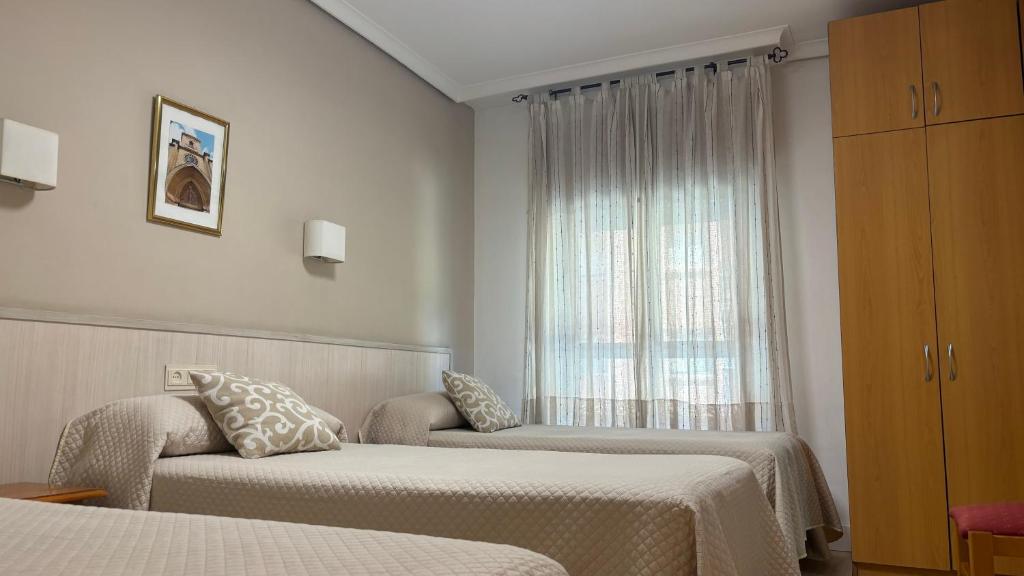 a hotel room with two beds and a window at Hostal Atienzar in Albacete
