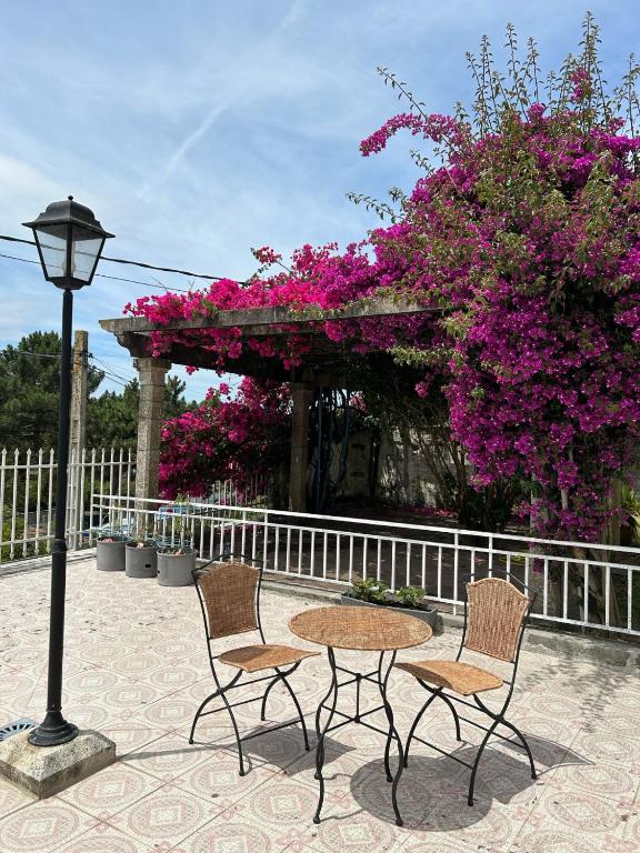 a table and two chairs and a lamp and flowers at Casa Kiros in Cangas de Morrazo