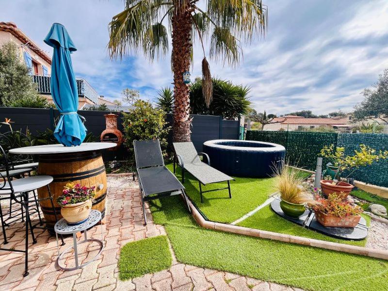 un jardin avec une table, des chaises et une fontaine dans l'établissement Villa climatisée avec jacuzzi, à La Londe-les-Maures