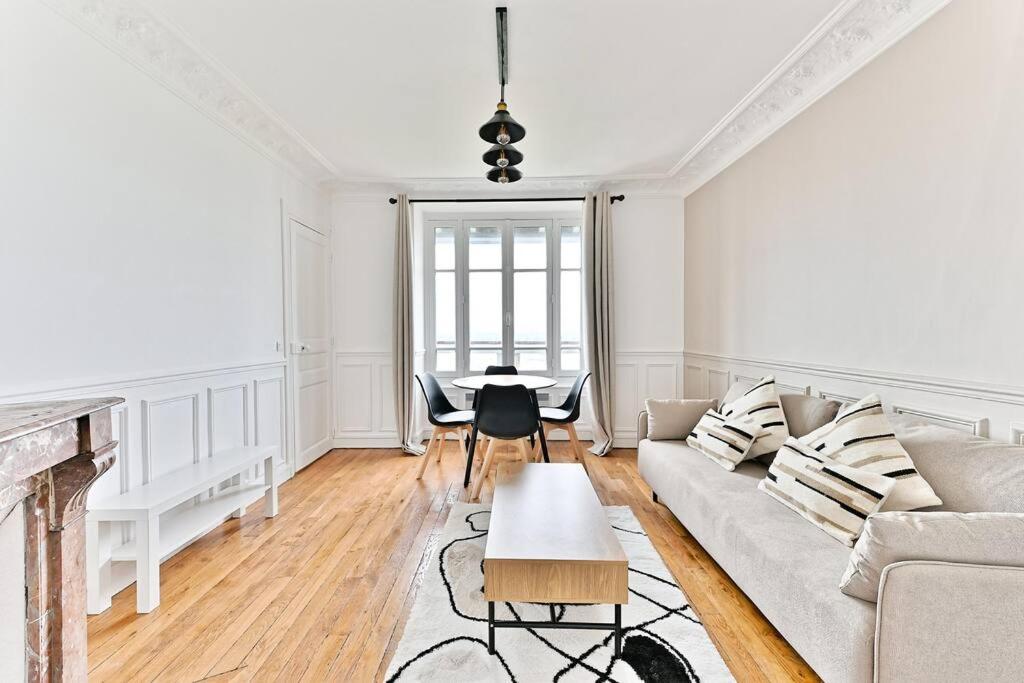 un salon blanc avec un canapé et une table dans l'établissement Appartement Spacieux Vue sur Paris Boulogne, à Puteaux