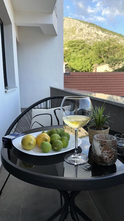 a plate of fruit and a glass of wine on a table at Sky hill residence Mostar in Mostar