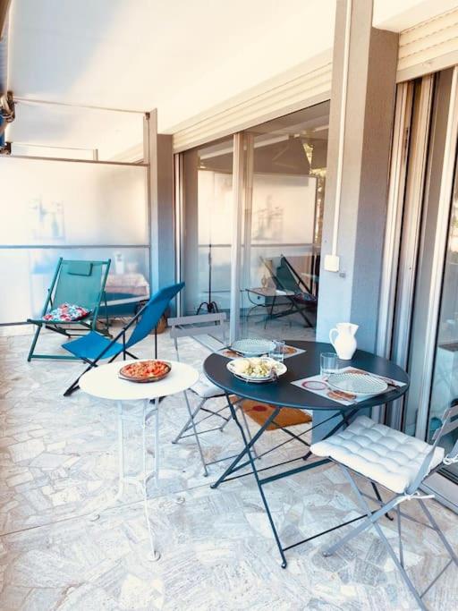 une pièce avec des chaises et des tables et une table avec de la nourriture dessus dans l'établissement Les nereides bord de mer calme lumineux parking, à Roquebrune-Cap-Martin