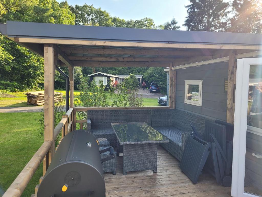 un pergolato con tavolo e sedie su un patio di Chalet bij Lente van Drenthe nabij meer a Gasselte