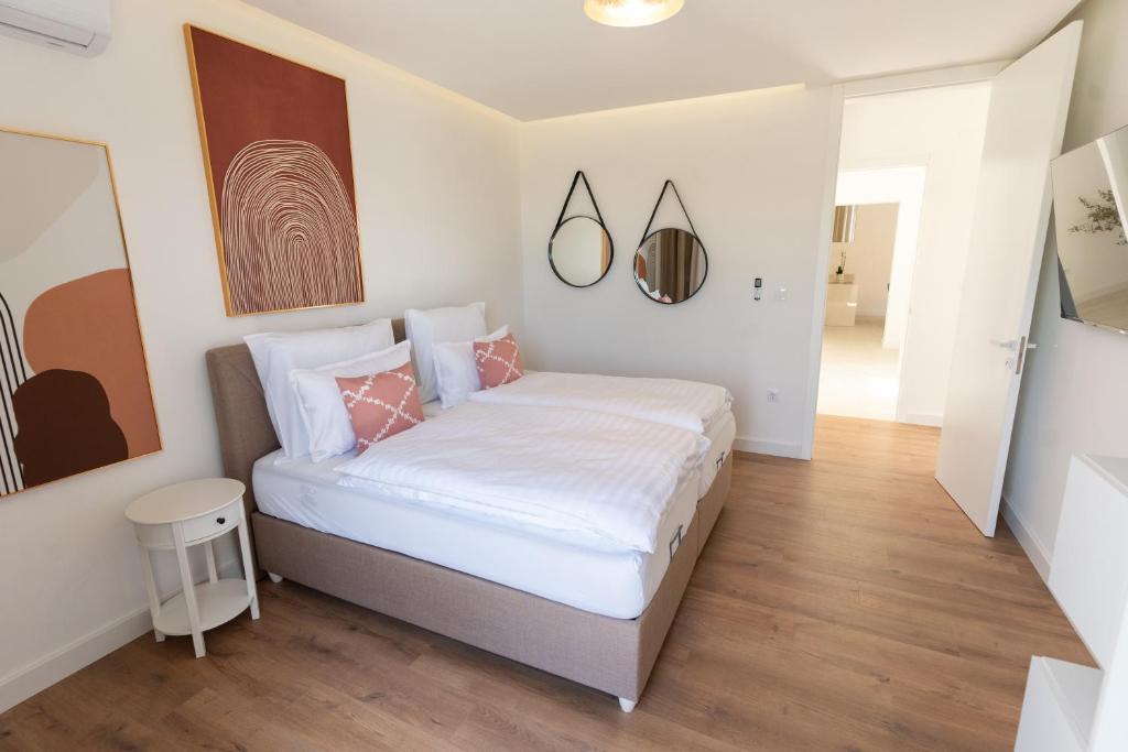 een slaapkamer met een bed met witte lakens en roze kussens bij Villa Bellevue in Mostar