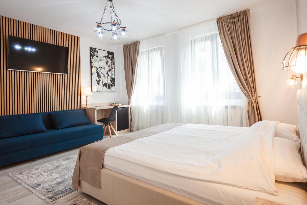 Un dormitorio con una cama grande y un sofá azul. en ARINI WHITE HOUSE, en Sibiu