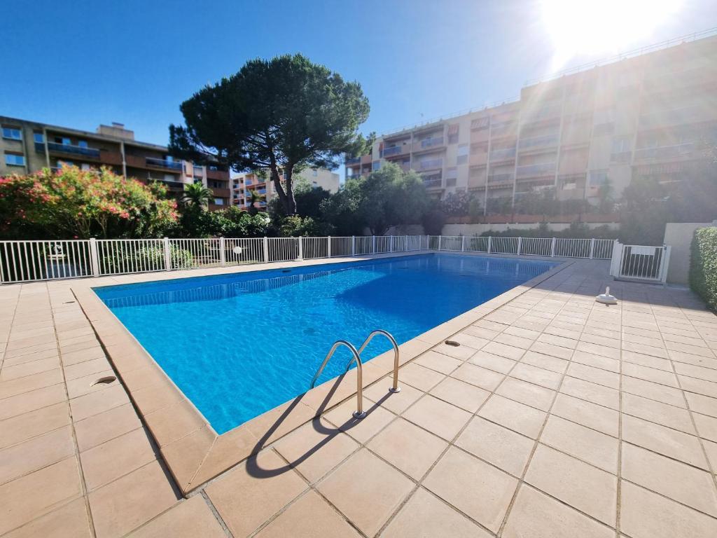 une piscine au milieu d'un immeuble dans l'établissement Le Repaire des Palmiers - T2 en centre-ville avec parking et piscine, à Hyères