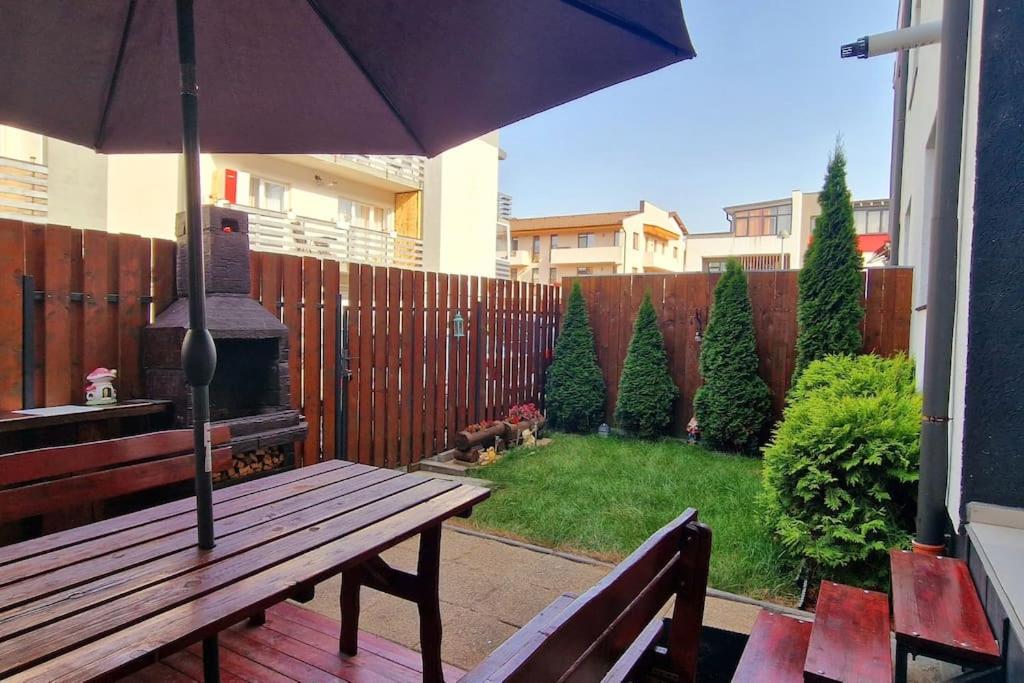 a patio with a wooden bench and an umbrella at FLH - Garden Grill Escape in Sibiu
