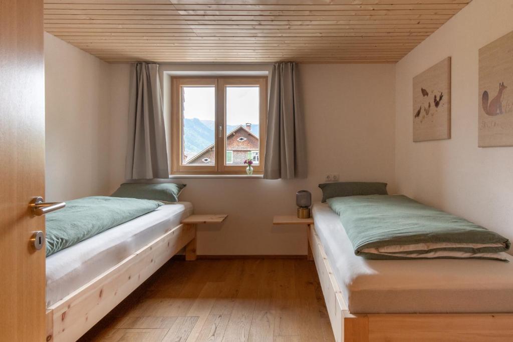 two beds in a room with a window at Ferienwohnungen am Dorfbach in Bezau
