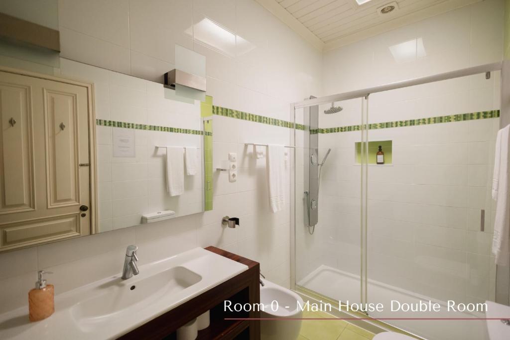 a white bathroom with a shower and a sink at Solar de Lalém in Maia