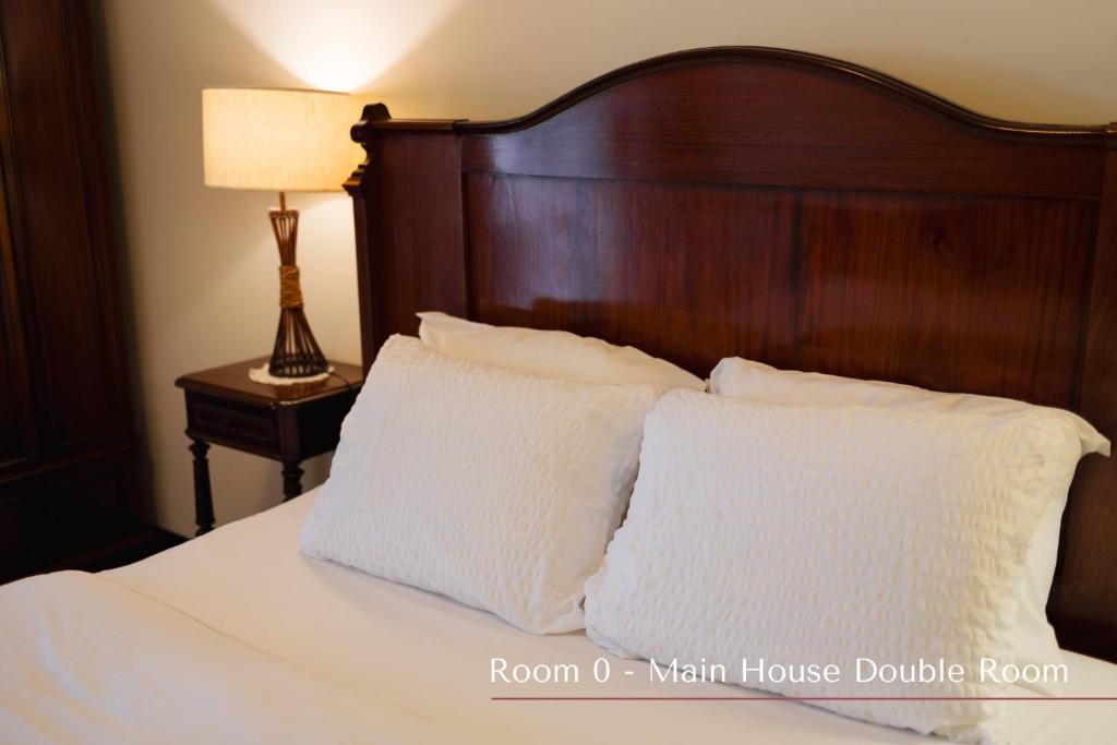 a bed with a wooden headboard and two pillows at Solar de Lalém in Maia