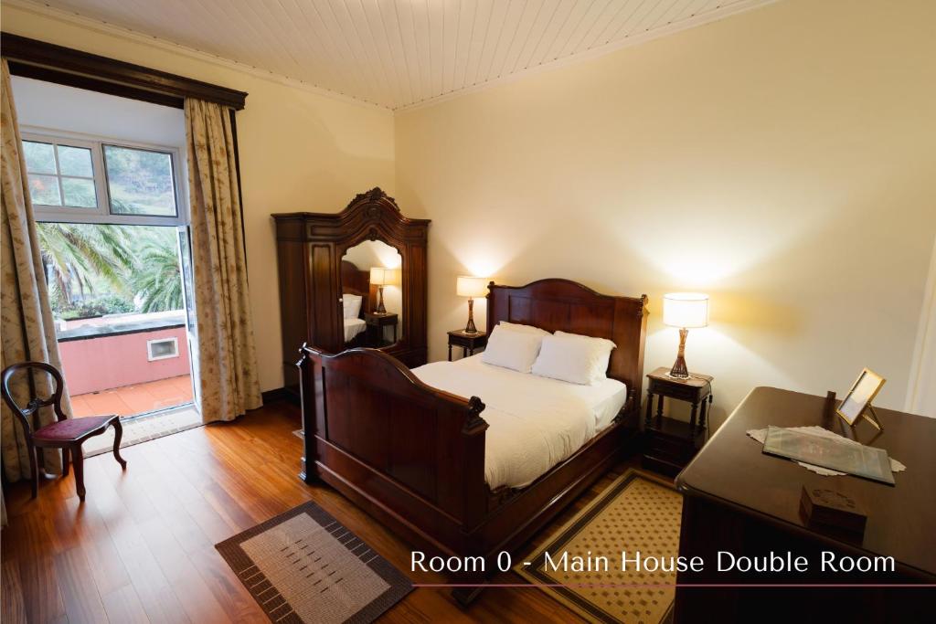 a bedroom with a bed and a desk and a window at Solar de Lalém in Maia