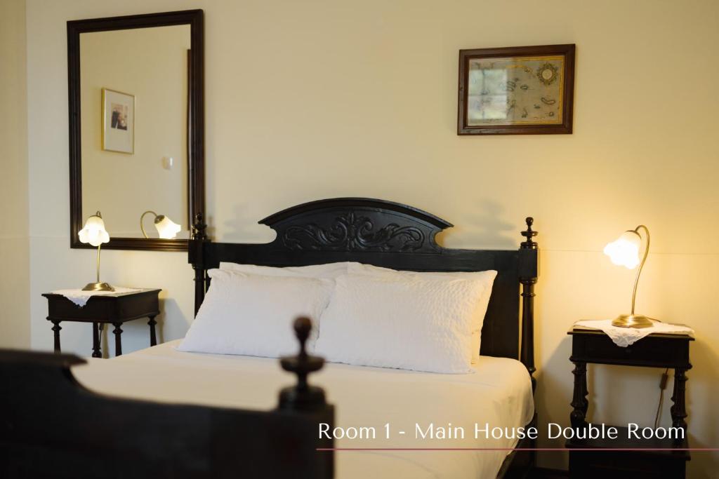 a bedroom with a bed with a black headboard and a mirror at Solar de Lalém in Maia