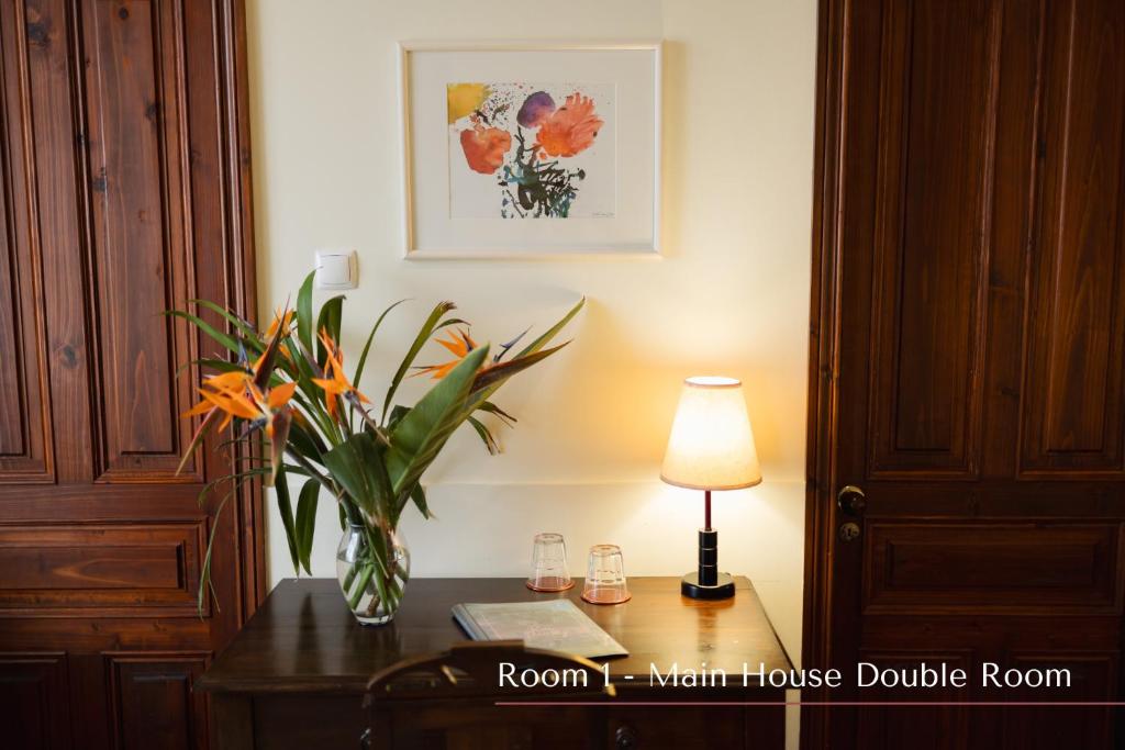 a vase of flowers on a table with a lamp at Solar de Lalém in Maia