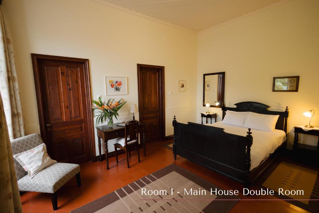 a bedroom with a bed and a chair and a table at Solar de Lalém in Maia