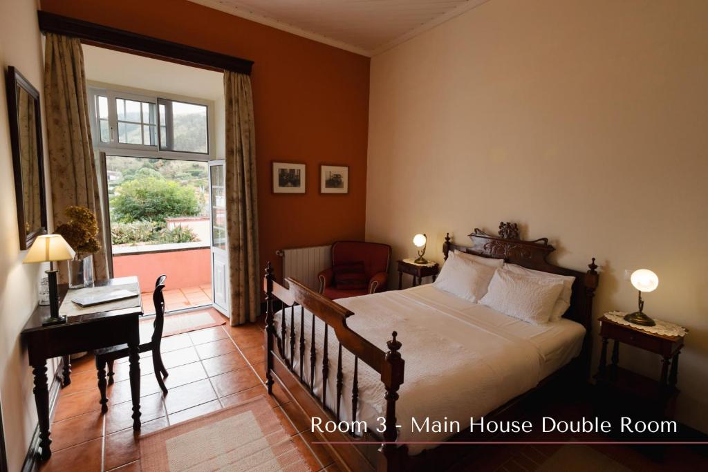 a bedroom with a bed and a desk and a window at Solar de Lalém in Maia