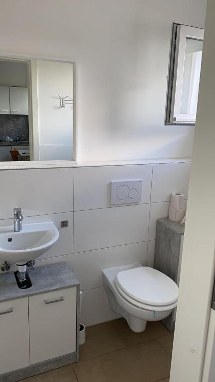 a white bathroom with a toilet and a sink at Hauptstraße 90 in Mehlingen