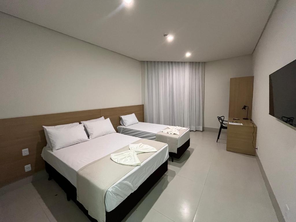 a hotel room with two beds and a flat screen tv at Hotel Premier Janauba in Janaúba