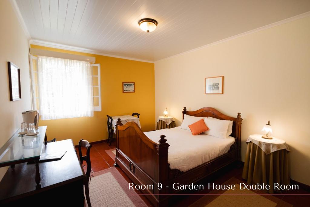 a bedroom with a bed and a table and a window at Solar de Lalém in Maia