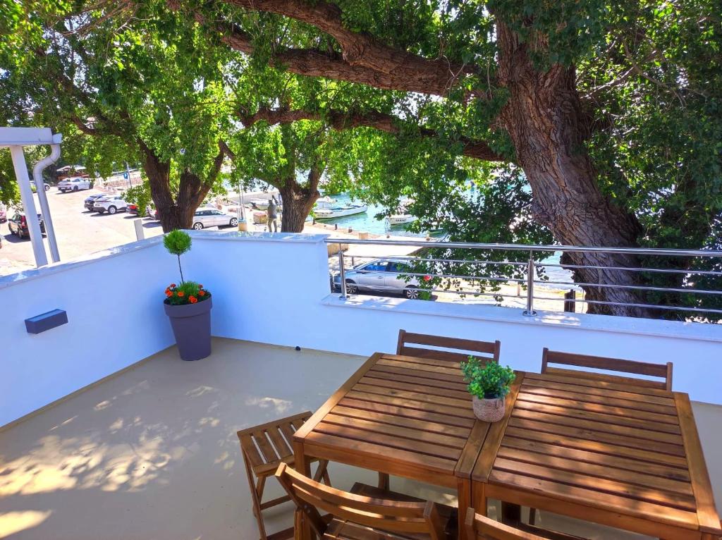 a wooden table and chairs on a balcony with a tree at Riva in Klenovica