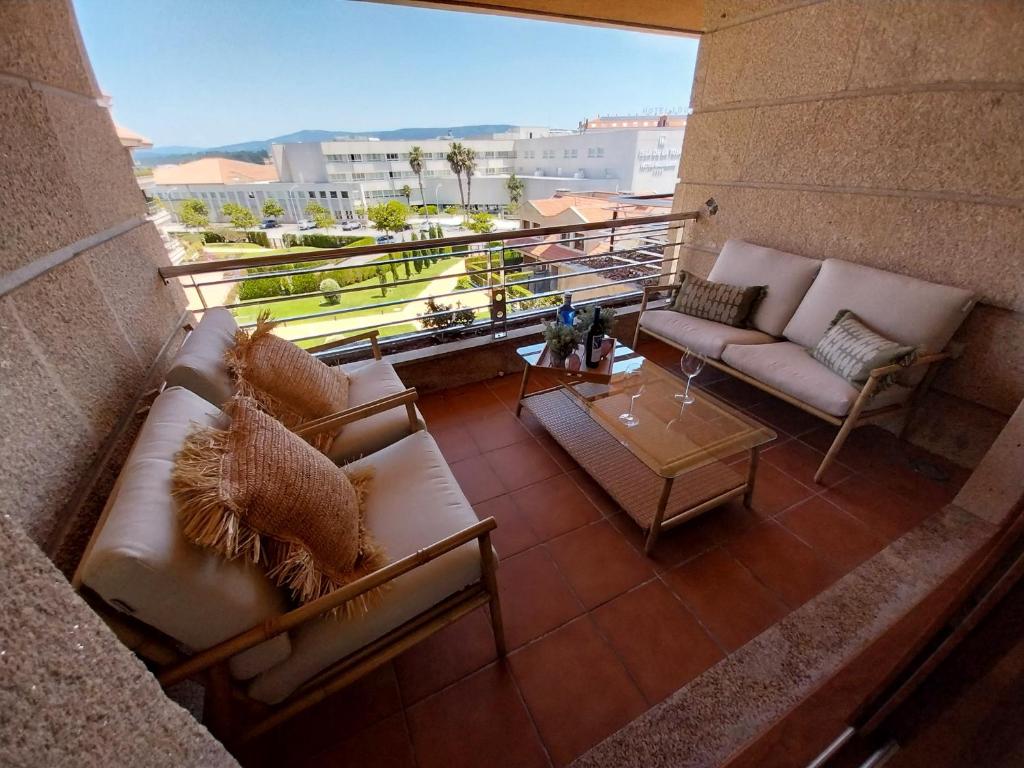 a living room with couches and a table on a balcony at PISO DÚPLEX - ISLA DE LA TOJA (O GROVE) in O Grove