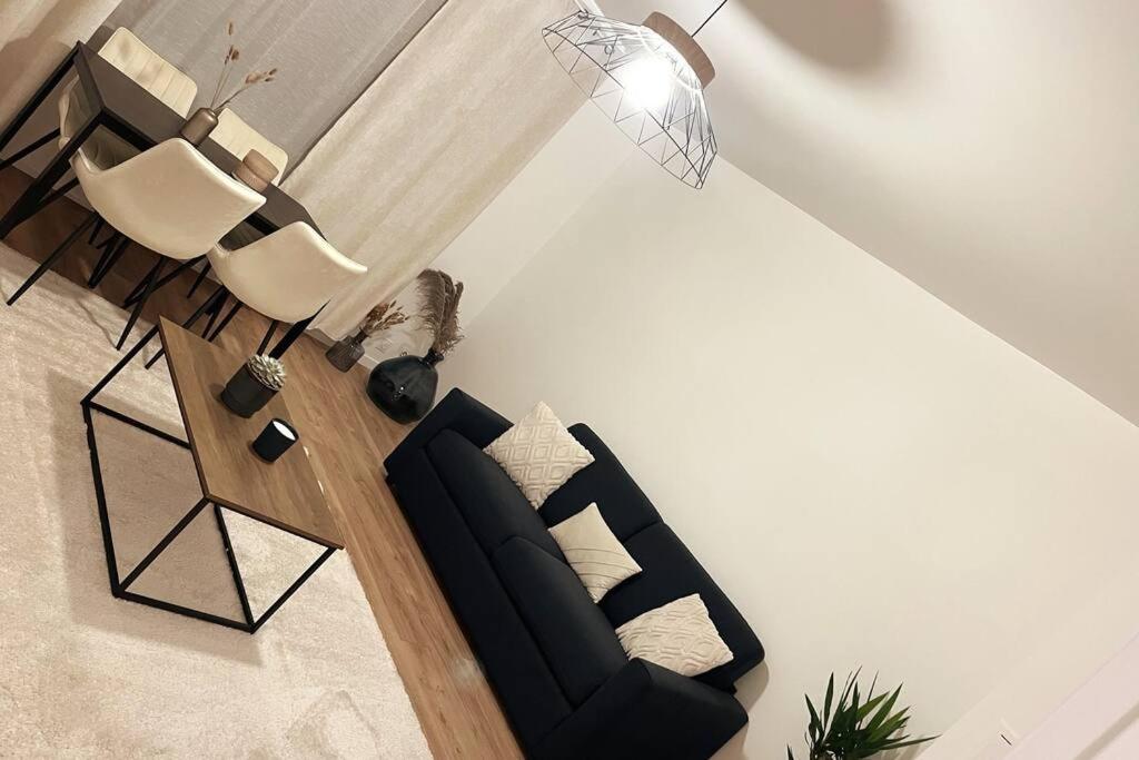 - un salon avec un canapé noir et des fauteuils blancs dans l'établissement Les Nuages de Sablon, à Clermont-Ferrand