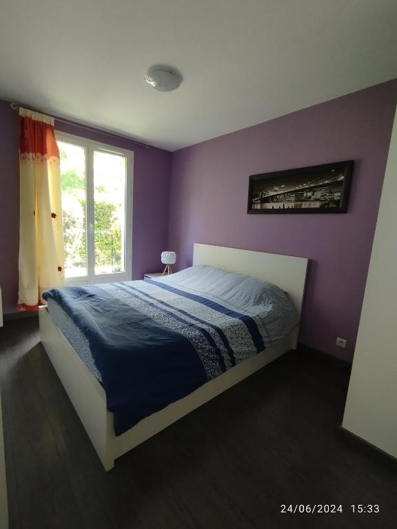 une chambre avec un lit aux murs violets et une fenêtre dans l'établissement appartement proche de Disney et val d Europe, à Chessy
