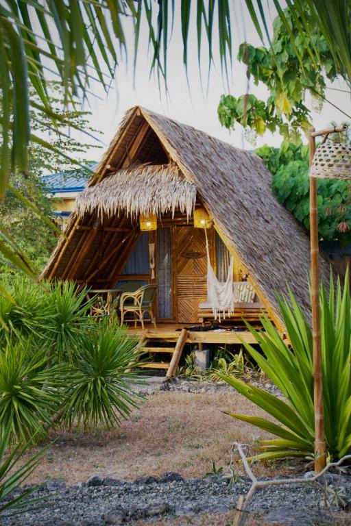 uma pequena cabana com telhado de palha num jardim em Tongo Hill Cottages em Moalboal