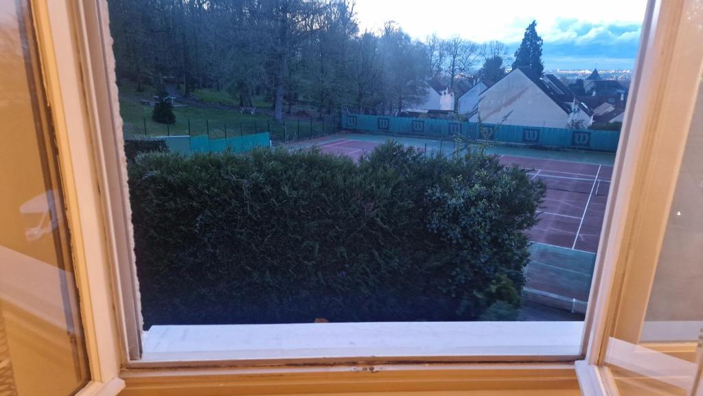 a window with a view of a tennis court at Chambre Jardin 1 in Vaujours