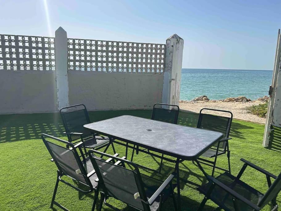 a table and chairs with the ocean in the background at Chalet a 2 metros de la playa in Rota