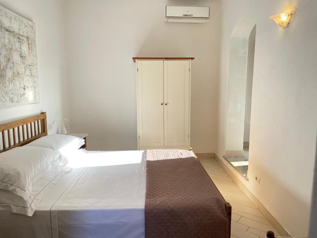 1 dormitorio con 1 cama blanca y armario en Mama House, en Porto Santo Stefano
