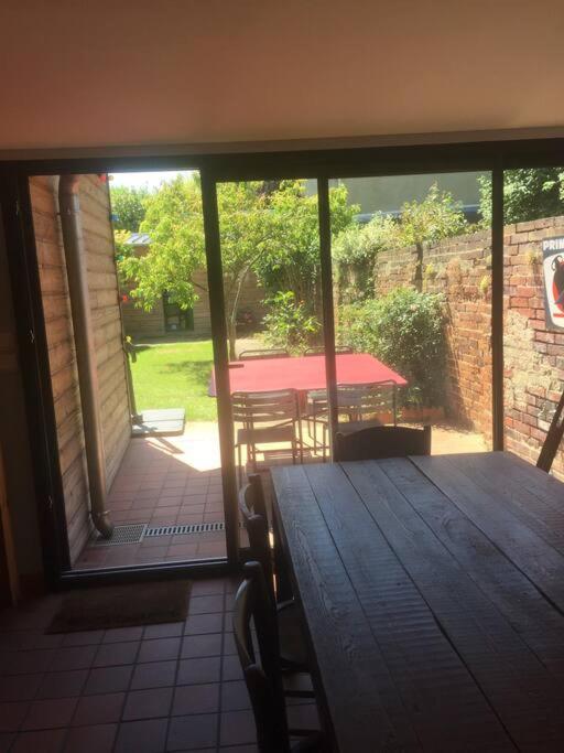 Elle offre une vue sur une terrasse couverte dotée d'une table. dans l'établissement Loue mancelle typique Le Mans Gare, au Mans