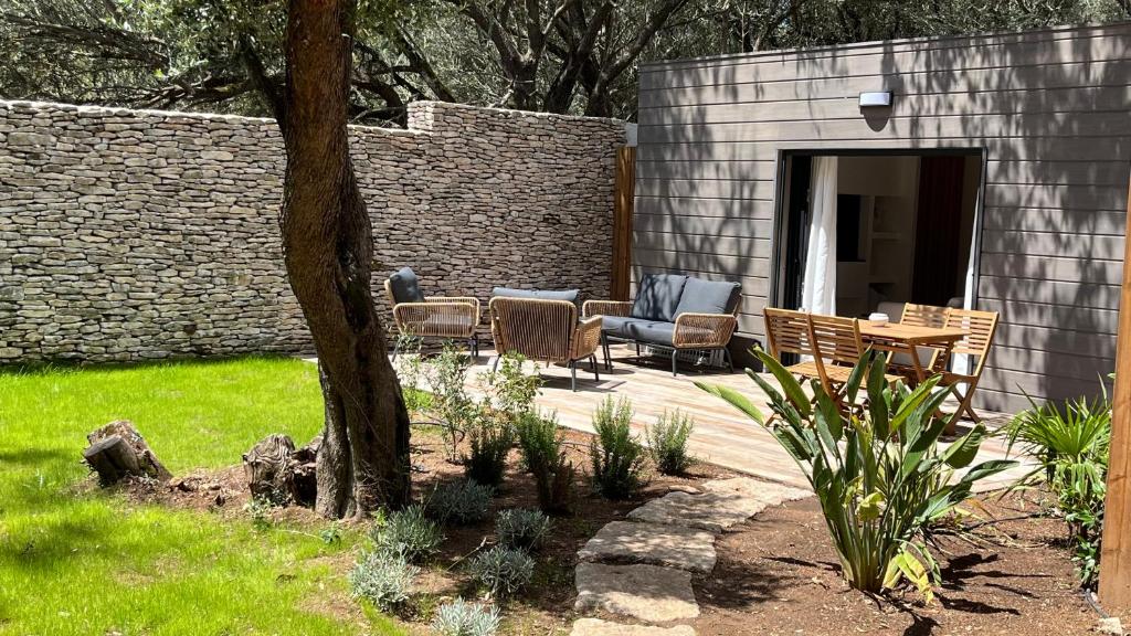 d'une terrasse avec des chaises, une table et un mur. dans l'établissement Perla Bianca, à Bonifacio