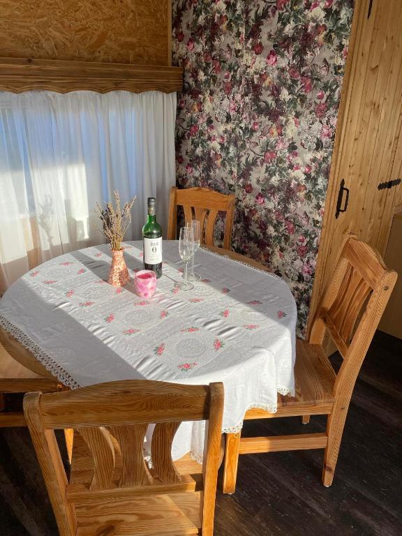 a table with a bottle of wine and two chairs at Przyczepa holenderska domek I in Przemysław