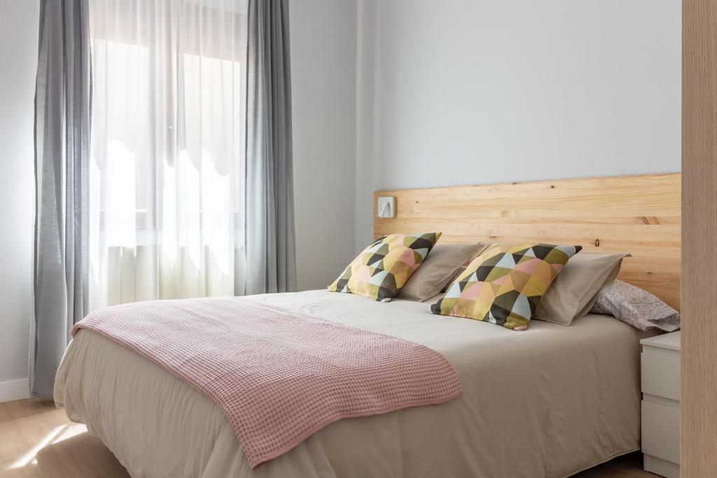 a bedroom with a bed with a wooden headboard and a window at AH Apartamento Urban Lena VUT6048AS in Pola de Lena
