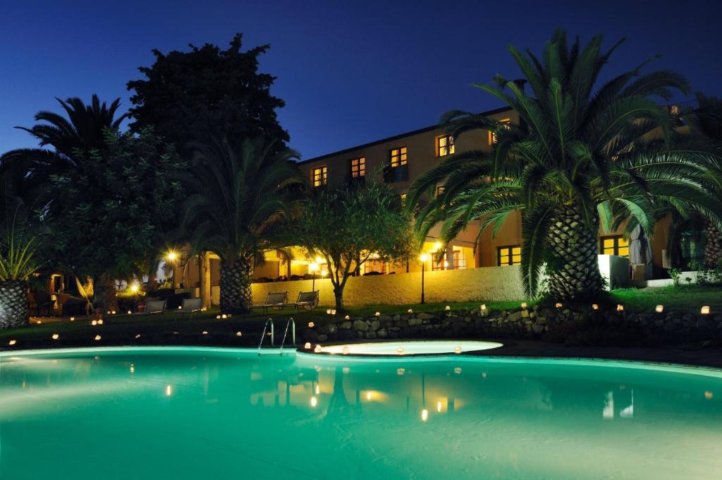 a swimming pool in front of a building at night at Alghero Resort Country Hotel & Spa in Alghero