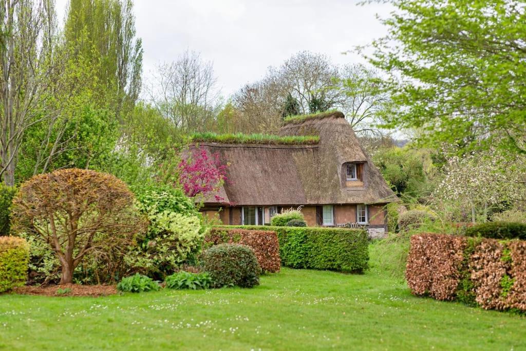 une maison ancienne avec un toit de chaume dans un jardin dans l'établissement Deux Chaumières Normandes, à La Mare Bardin