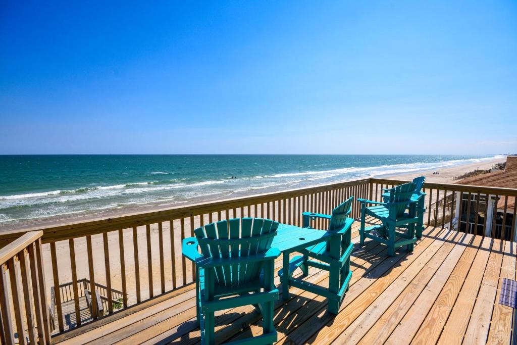 drie stoelen en een tafel op een terras met uitzicht op het strand bij Beach Bunns in Surf City
