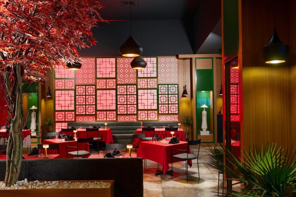 a restaurant with red tables and chairs in a room at Liberty Kuşadası in Kusadası