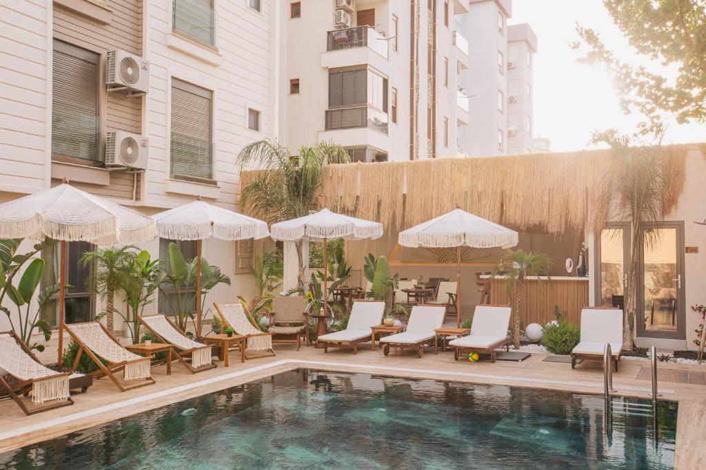 ein Pool mit Liegestühlen und Sonnenschirmen neben einem Gebäude in der Unterkunft Los Suites in Antalya