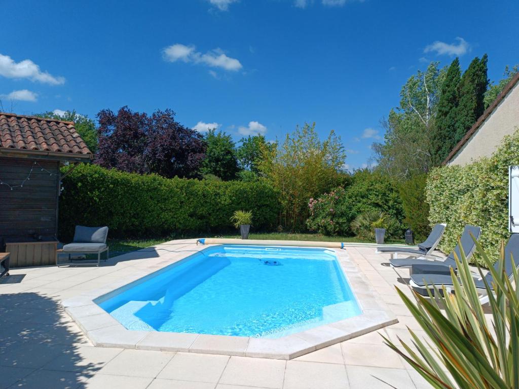 une piscine dans une cour avec des chaises et une maison dans l'établissement Villa 150 m2 Bordeaux Océan Porte du Médoc, à Saint-Aubin-de-Médoc