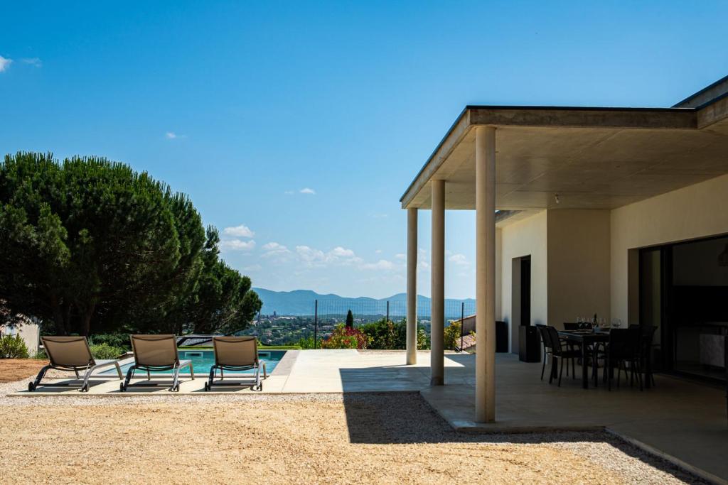 une maison avec un patio avec des chaises et une table dans l'établissement Villa des pins - sud Ardèche 4 lits - 6 pers, à Lablachère