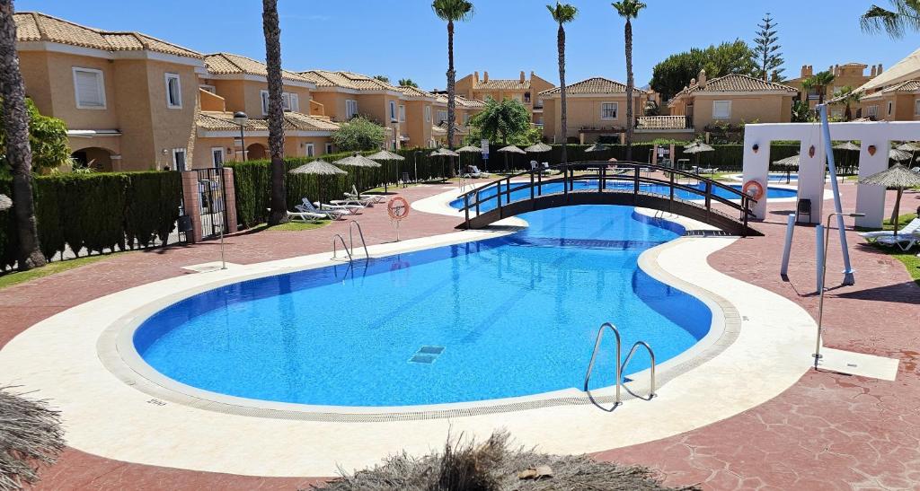 a swimming pool with a bridge in a villa at Homes of Spain, Casa Duplex Playas del Sur, 400m del mar , WIFI in Playas de Vera
